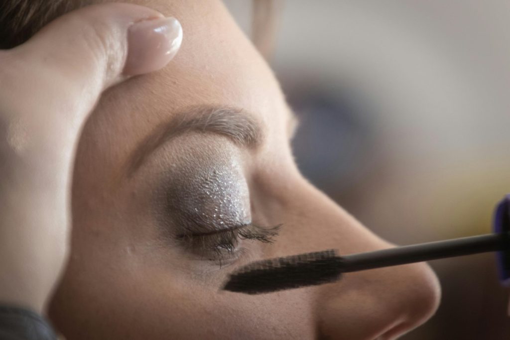 Das Augenlid einer Frau ist zart mit glamourösem, schimmerndem Lidschatten und Mascara bemalt.